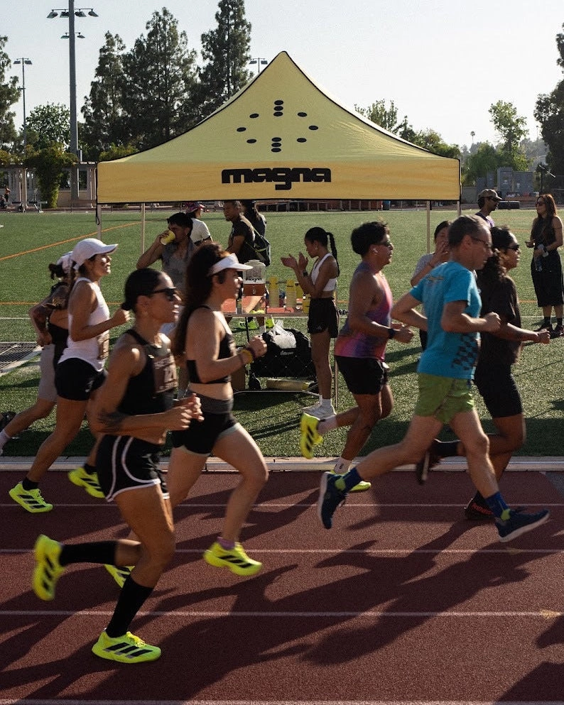 Runners on a track passing a yellow magna tent