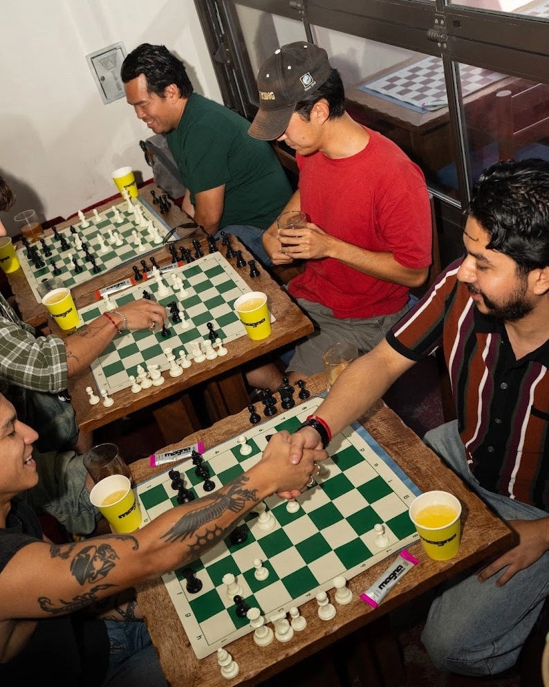 People playing chess at a table with yellow magna cups