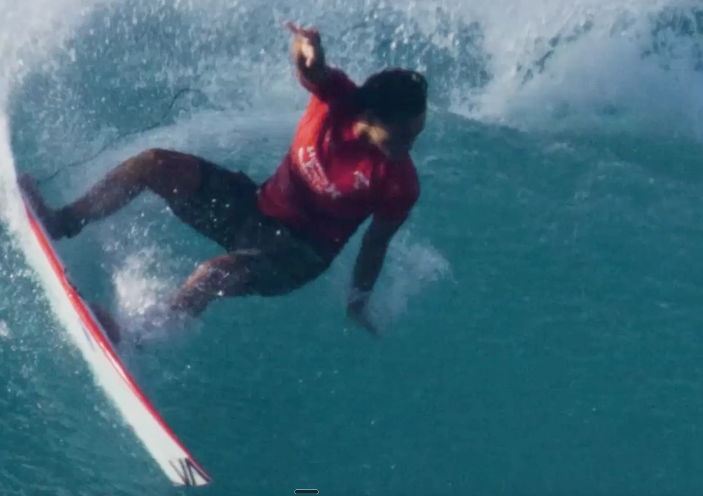 Surfer in a red jersey carving a turn on a wave