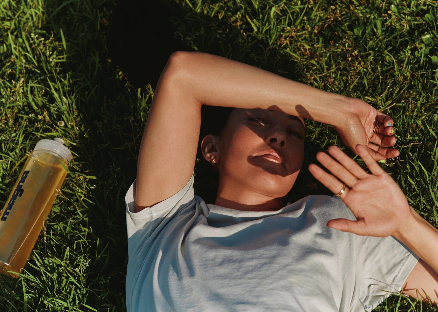 Person lying on grass with a water bottle nearby.