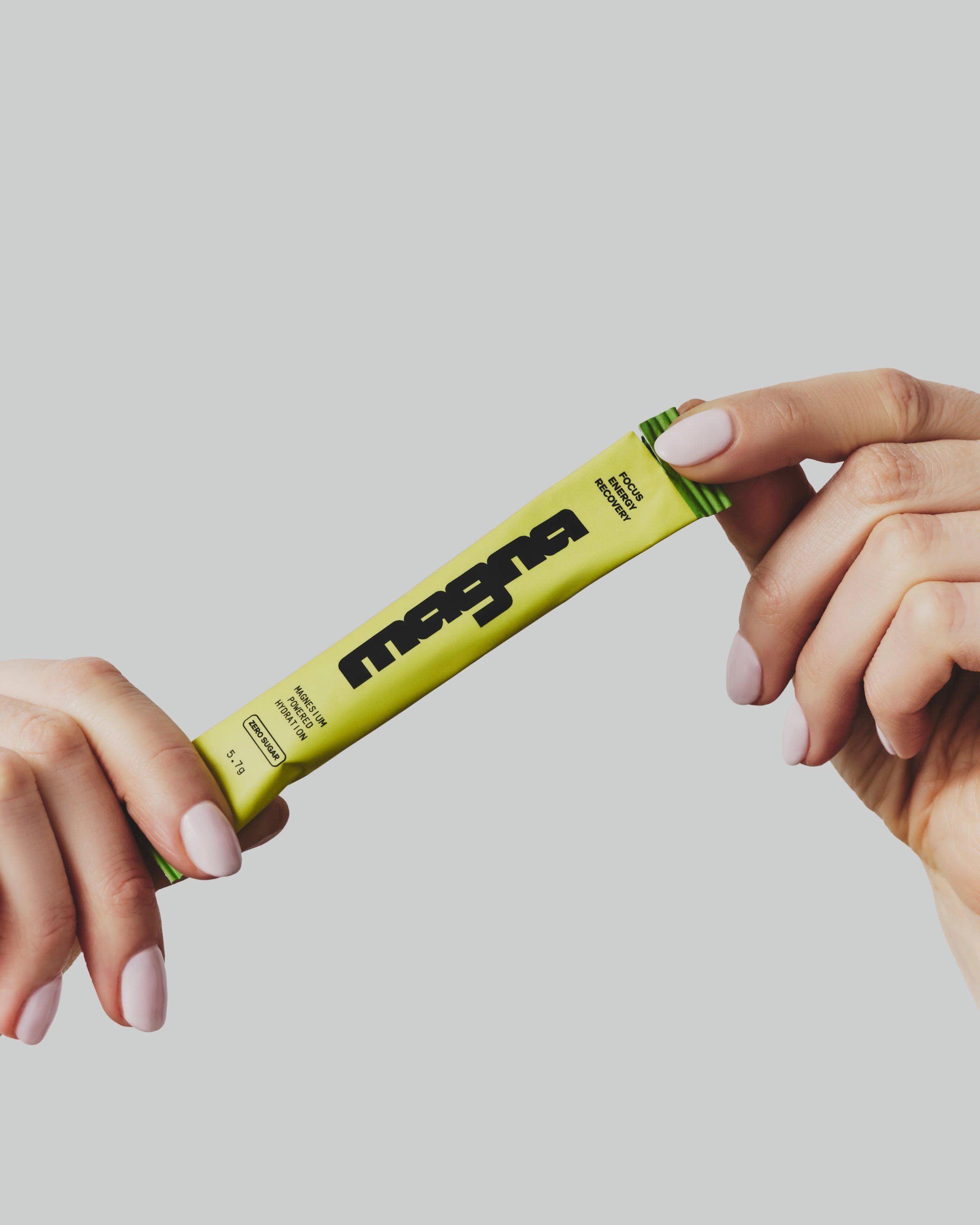 Two hands tearing open a yellow magna stick pack